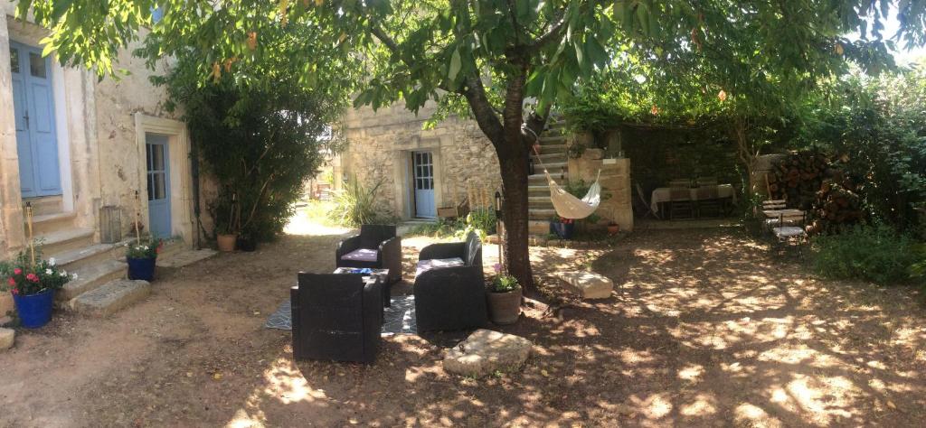un patio con sofás y un columpio bajo un árbol en La Garrigue, en Galargues