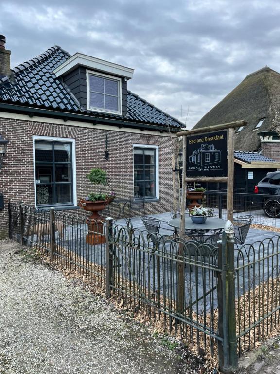 a fence in front of a house with a sign at Bed and Breakfast Lokaal Wadway in Spanbroek