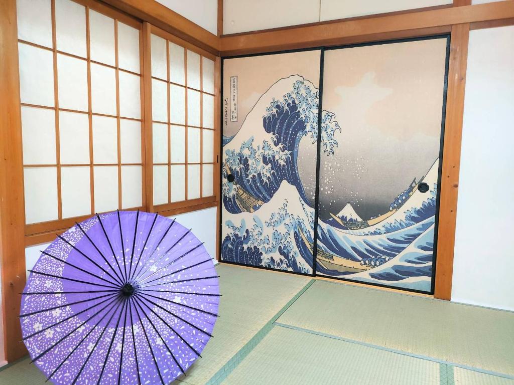 a purple umbrella sitting in a room with a painting at Masaki 1chome house in Nagoya