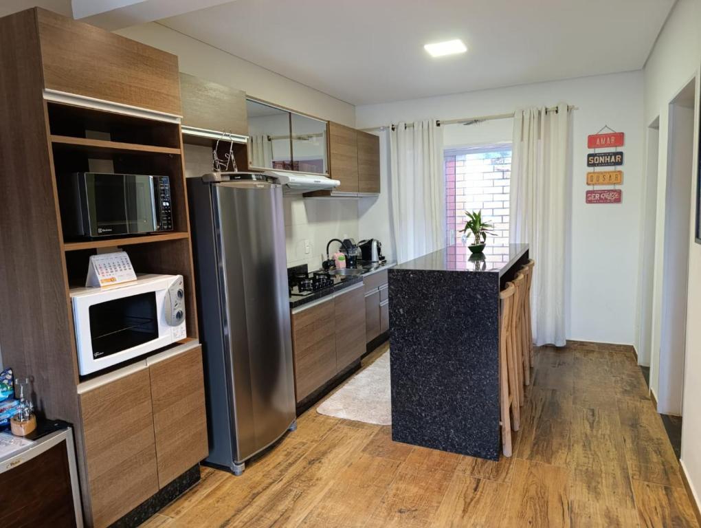 W kuchni znajduje się lodówka ze stali nierdzewnej i kuchenka mikrofalowa. w obiekcie Residencial Luce Del Sole - Casa Nº 5 w mieście Joinville