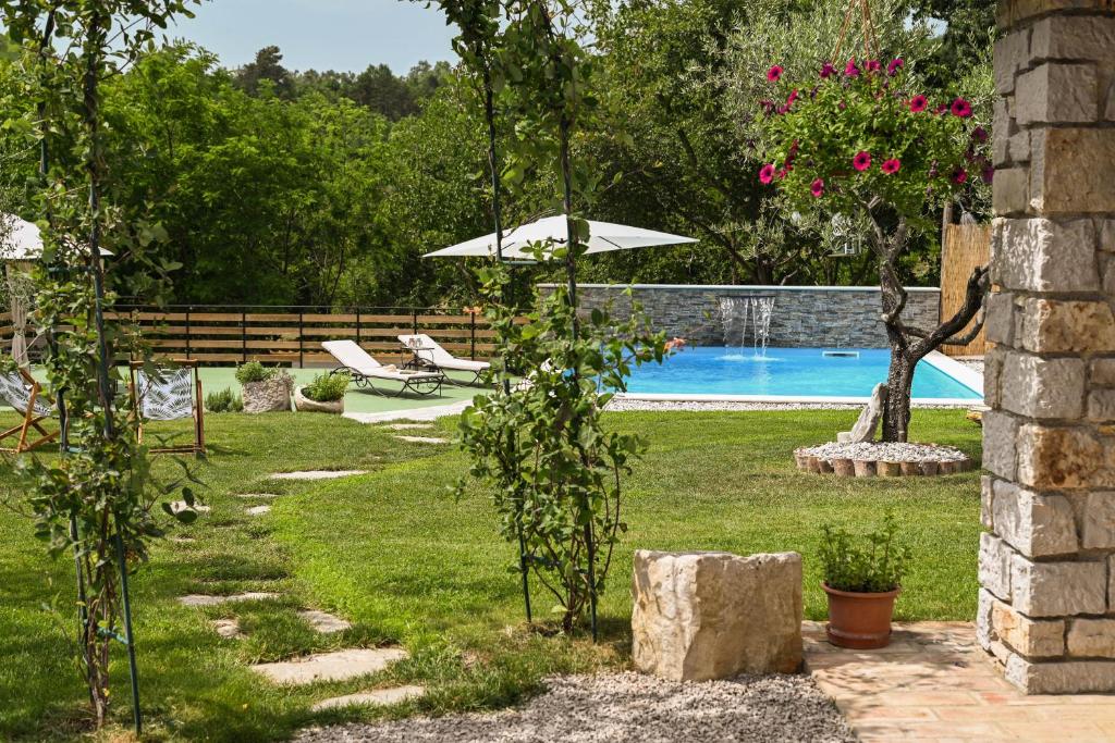 a garden with a swimming pool and an umbrella at Boutique Villa Pucinum in Buzet