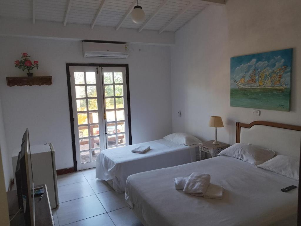 a hotel room with two beds and a window at Pousada Éden in Angra dos Reis