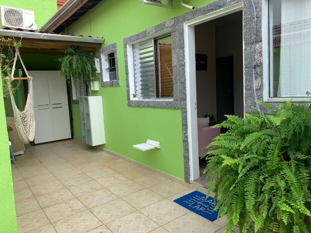 ein grünes Haus mit einer Tür und einer Terrasse in der Unterkunft Casa de praia com ar condicionado. in São Sebastião
