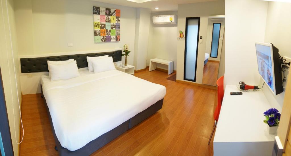 1 dormitorio con 1 cama blanca grande y espejo en Ma Non Nont Hotel & Apartment, en Nonthaburi
