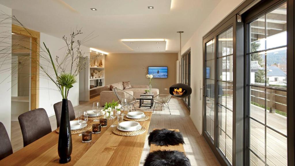 a dining room and living room with a table and a fireplace at LA MAISON Titisee - Boutique Design Villa im Schwarzwald in Titisee-Neustadt