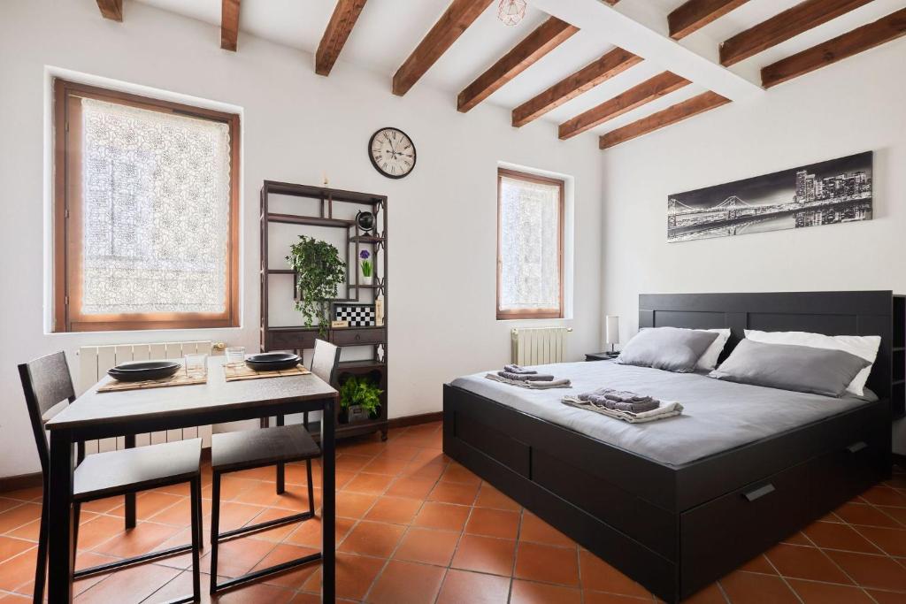 ein Schlafzimmer mit einem Bett, einem Tisch und einer Uhr in der Unterkunft Il Lusso Della Semplicità in Piacenza