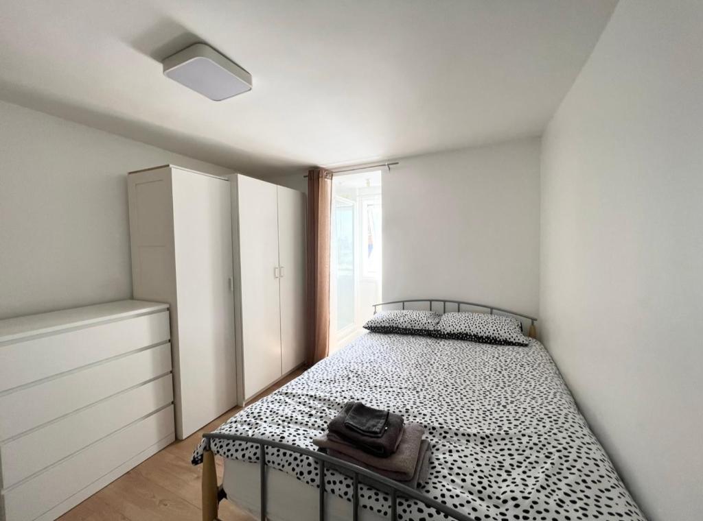 Schlafzimmer mit einem Bett mit einer schwarzen und weißen Bettdecke in der Unterkunft Cosy Studio - London in London