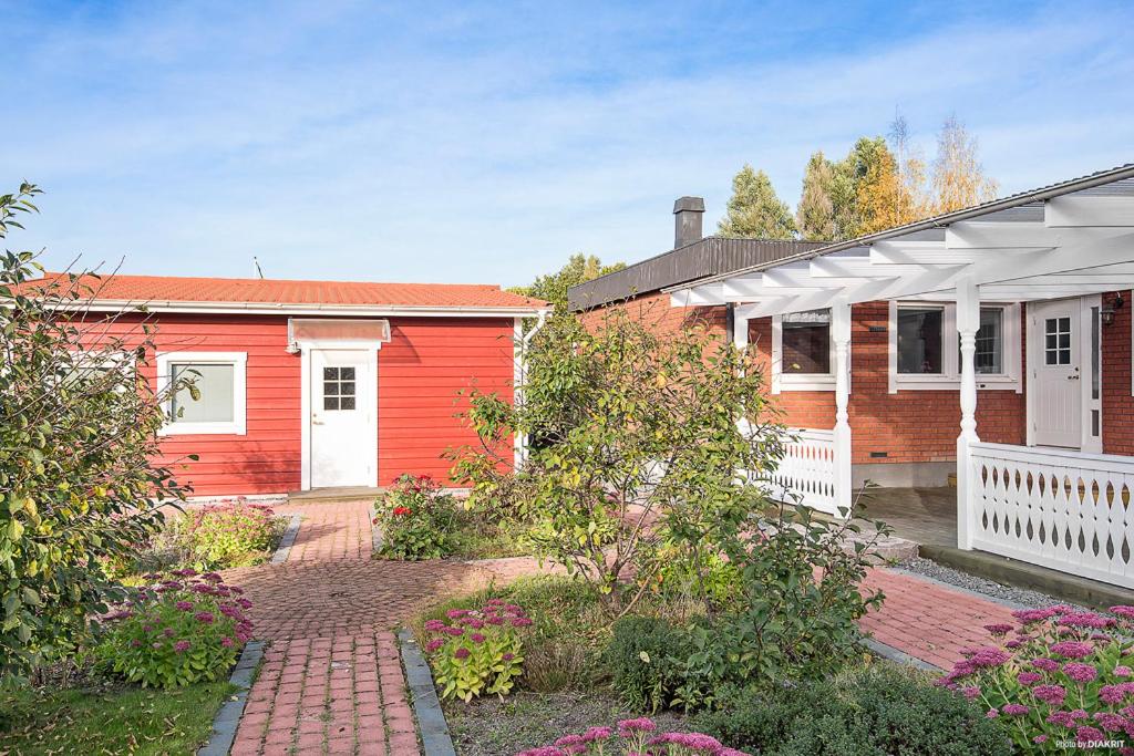 een rood-wit huis met een bakstenen tuin bij Gäststugan in Uppsala