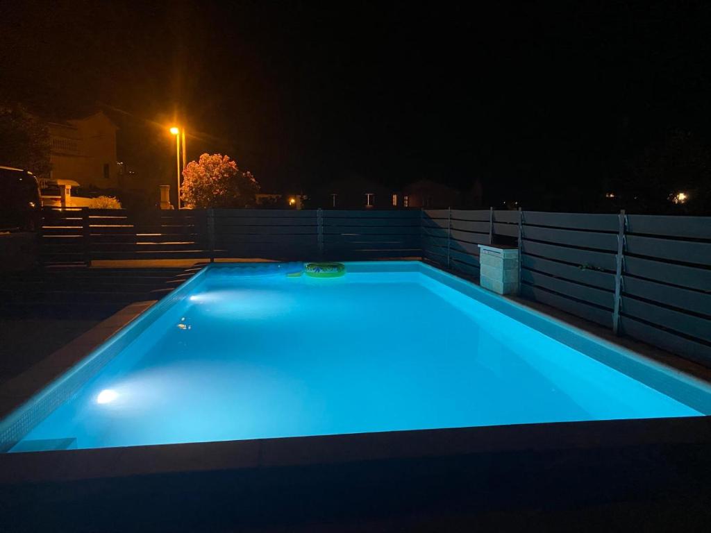 una piscina notturna con luci blu di Apartman Telar a Vodice