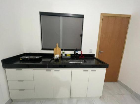 a kitchen with a black counter top and a sink at Flat completo Aparecida de Goiânia in Aparecida de Goiania
