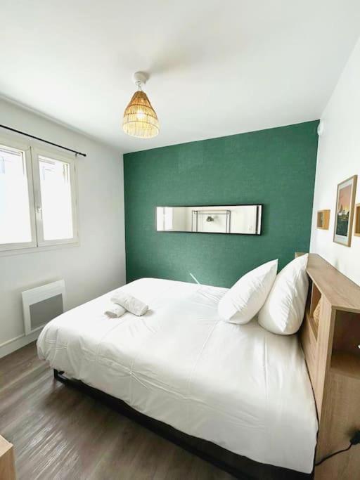 een slaapkamer met een wit bed en een groene muur bij Appartement cosy avec terrasse et parking, 4 pers. in Étampes