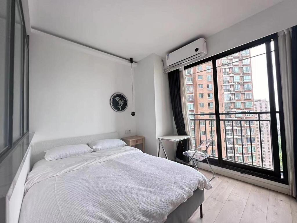 a bedroom with a white bed and a large window at 同济佳苑公寓 in Shanghai