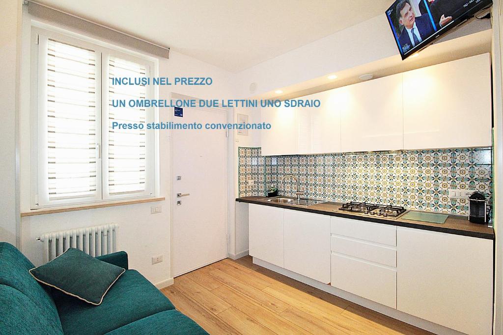 una cocina con armarios blancos y un sofá verde en Casa Vacanze del Vicario, en San Benedetto del Tronto