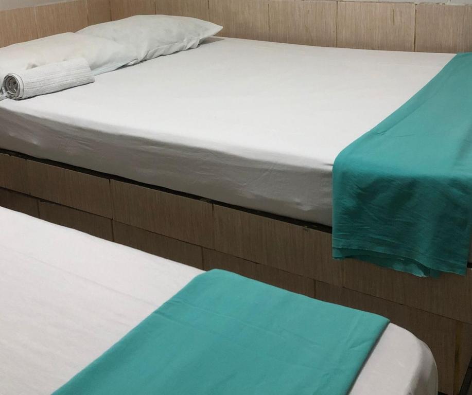 2 camas individuales con sábanas azules y blancas en Pousada Aldo, en Delmiro Gouveia