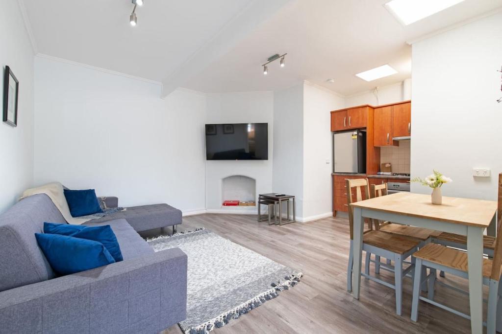 ein Wohnzimmer mit einem blauen Sofa und einem Tisch in der Unterkunft Convenient and Cosy 1BD Unit with free wine in Wayville