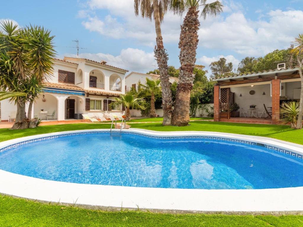 a pool in front of a house with palm trees at Holiday Home Santiago - RDB100 by Interhome in Roda de Bará