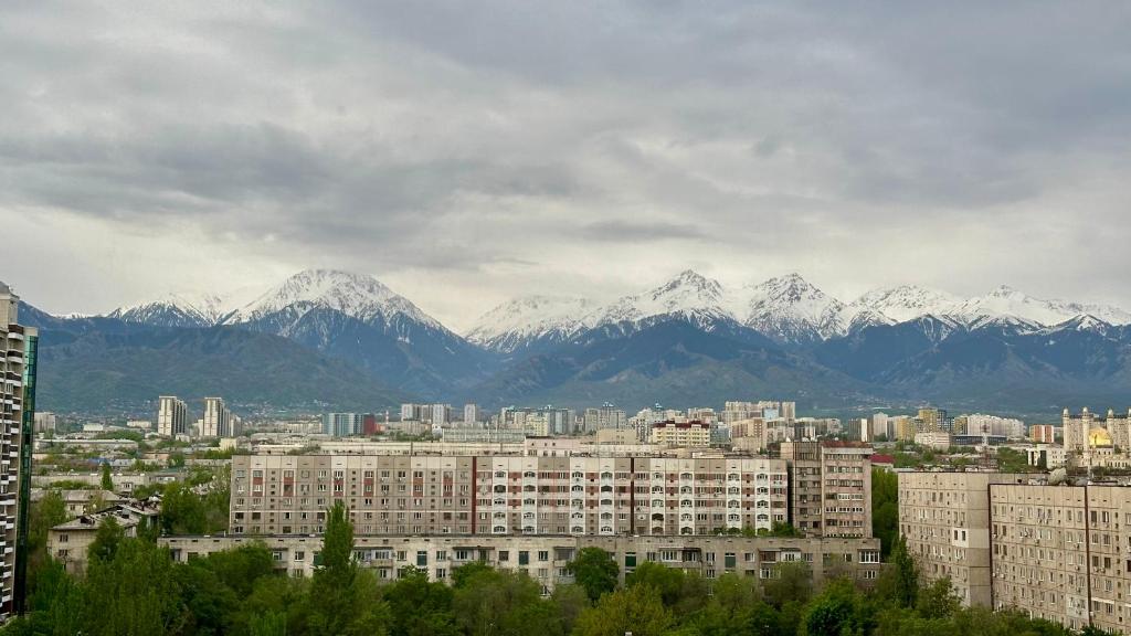 a city with snow capped mountains in the background at Стильная квартира в Алматы in Almaty