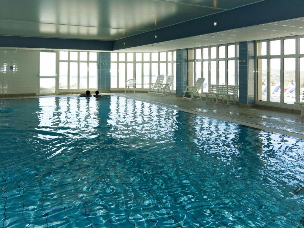 a large swimming pool with blue water in a building at Apartment Reine Marine- T2 SUD by Interhome in Saint Malo