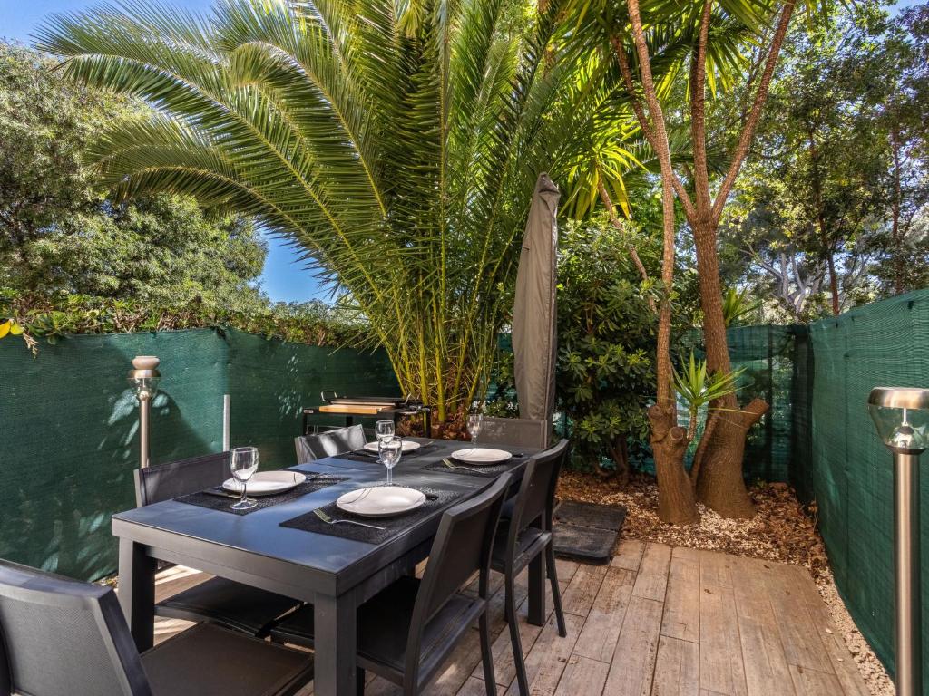 une table et des chaises noires sur une terrasse avec des palmiers dans l'établissement Studio Les Mimosas Bleus-4 by Interhome, à Bormes-les-Mimosas