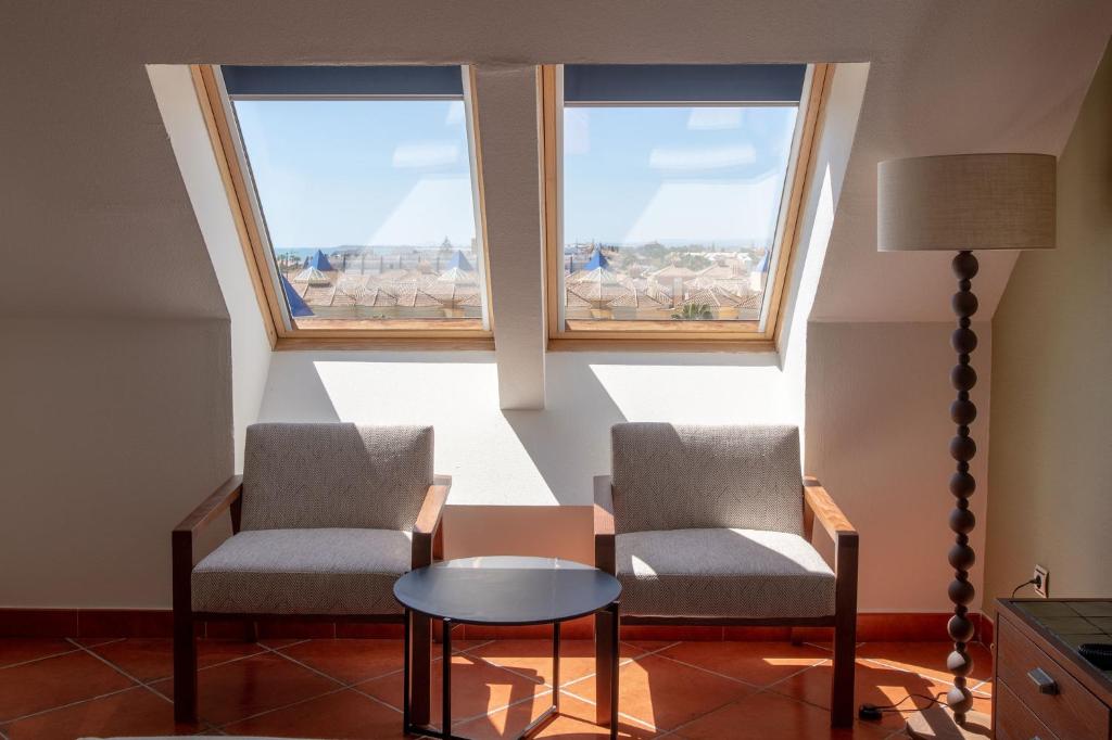 two chairs and a table in a room with two windows at Puerto Antilla Grand Hotel in Islantilla
