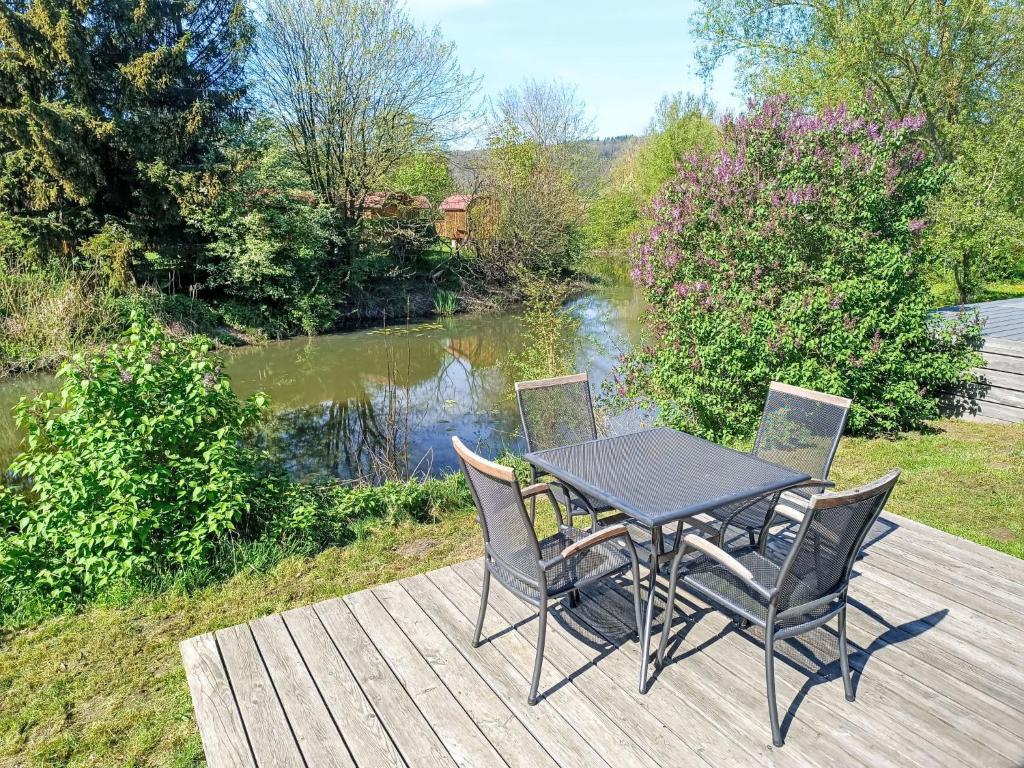 a table and chairs on a deck next to a river at Holiday Home Tiny Haus Sonnendeck by Interhome in Beilngries