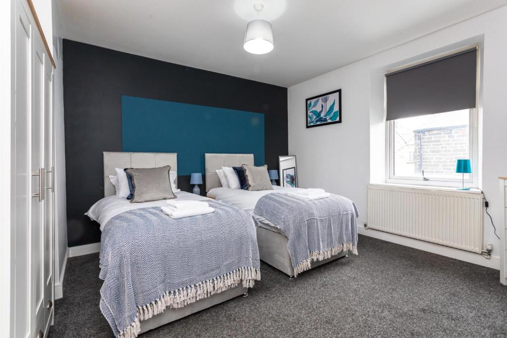 a bedroom with two beds and a blue wall at Stylish Three Bed House Burnley in Burnley