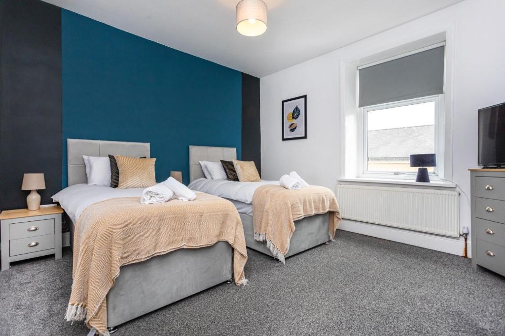 um quarto com 2 camas e uma parede azul em Fabulous 3 bed house in Burnley em Brierfield