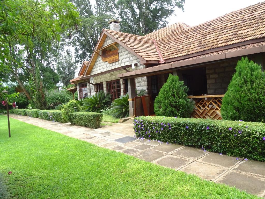 a house with a green yard and bushes at Le Pristine Wellness and Healing Hotel in Nyeri