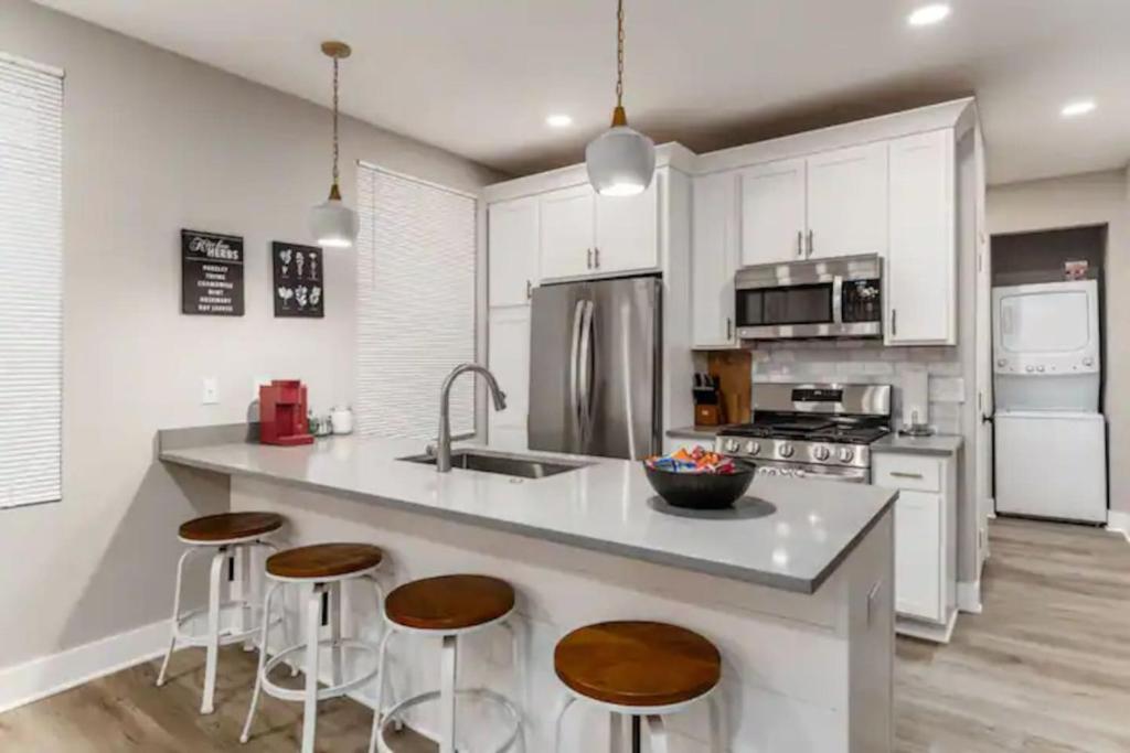 a kitchen with white cabinets and a island with bar stools at 2 homes side by side downtown with fenced yard and hot tub in Columbus