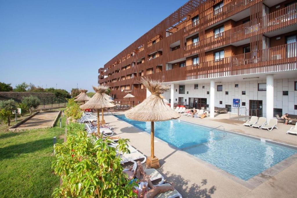 ein Hotel mit einem Pool mit Sonnenschirmen in der Unterkunft Cosy Gaïa - Appt climatisé avec piscine partagée in Sète