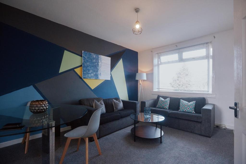 a living room with a couch and a table at Modern And Vibrantly Designed Apartment in Motherwell