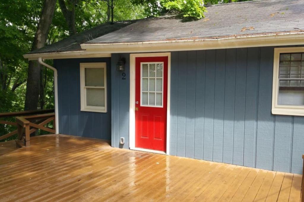 a blue house with a red door and a wooden deck at Cottage 2 Lees Ford Marina in Nancy