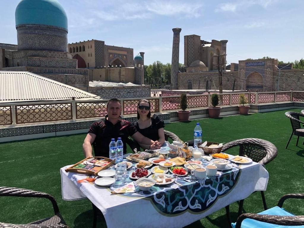 un hombre y una mujer sentados en una mesa con comida en KAMILA Hotel Boutique, en Samarkand