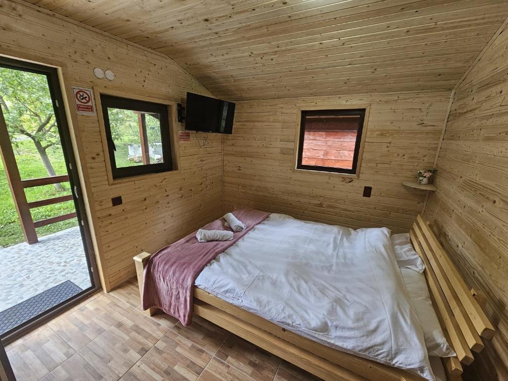 a bedroom in a wooden cabin with a bed in it at Casute la "Doi pasi de Castel" in Hunedoara