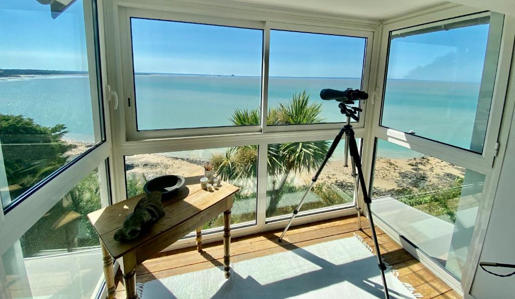a camera on a tripod in a room with a view of the ocean at Cottage Pêcheur + Annexe 12pers vue Mont St-Michel in Champeaux