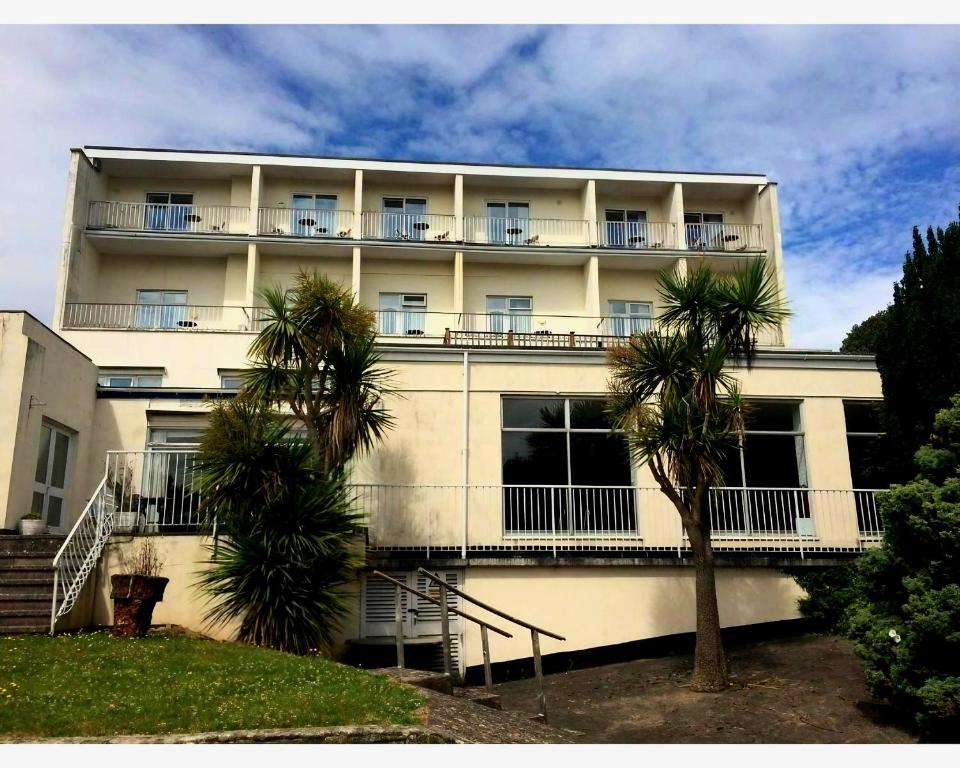 a white building with palm trees in front of it at Richmond Hotel in Torquay