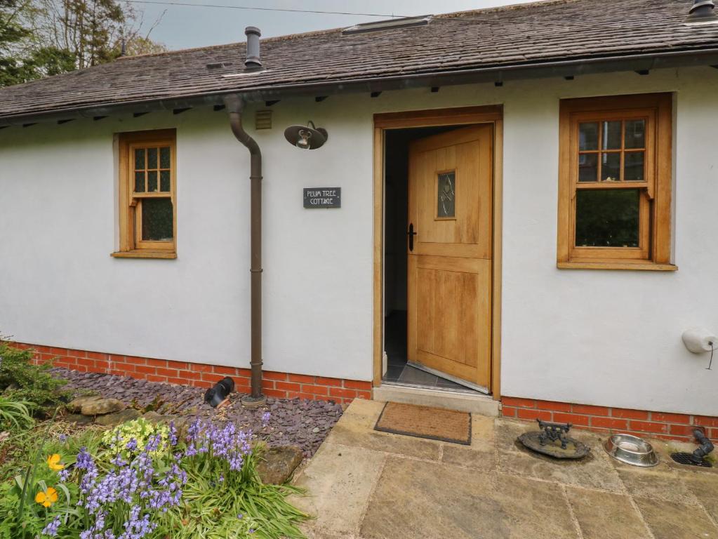 a white house with a wooden door at Plum Tree Cottage in Castleton