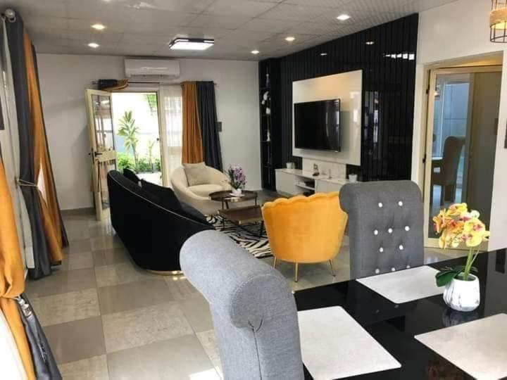 a living room with a couch and chairs and a television at Villa trois chambres avec piscine in Cotonou