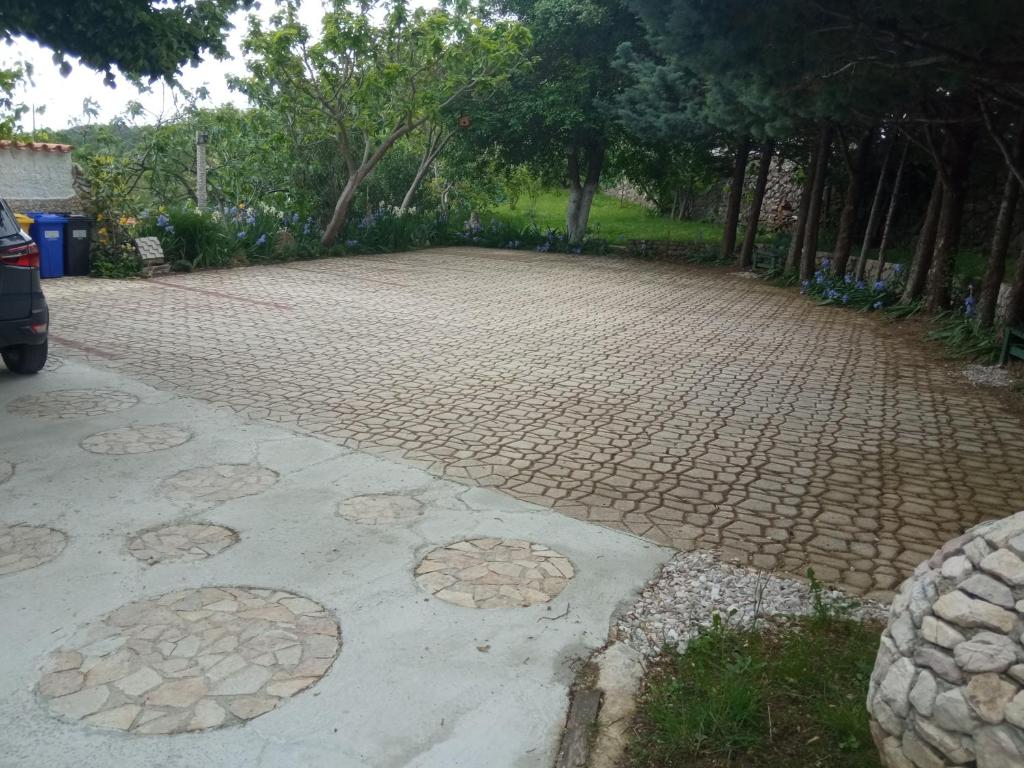 a cobblestone driveway with trees in a park at KATY&MLADEN in Baška