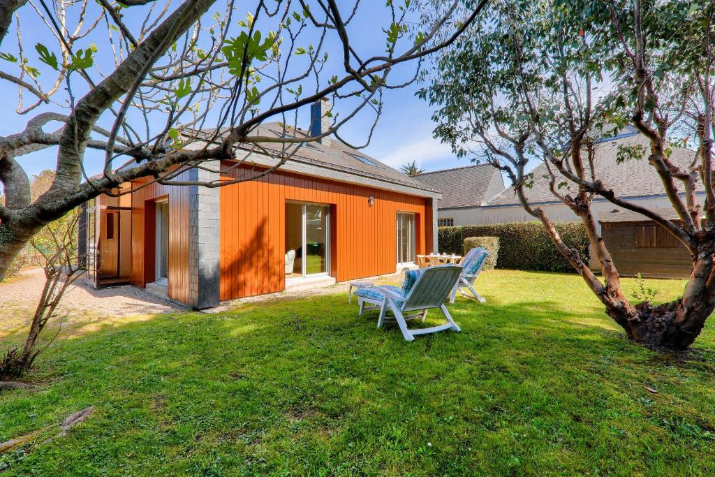 une maison orange avec deux chaises dans la cour dans l'établissement St Pierre de Quiberon - Maison 6 Personnes, à Saint-Pierre-Quiberon