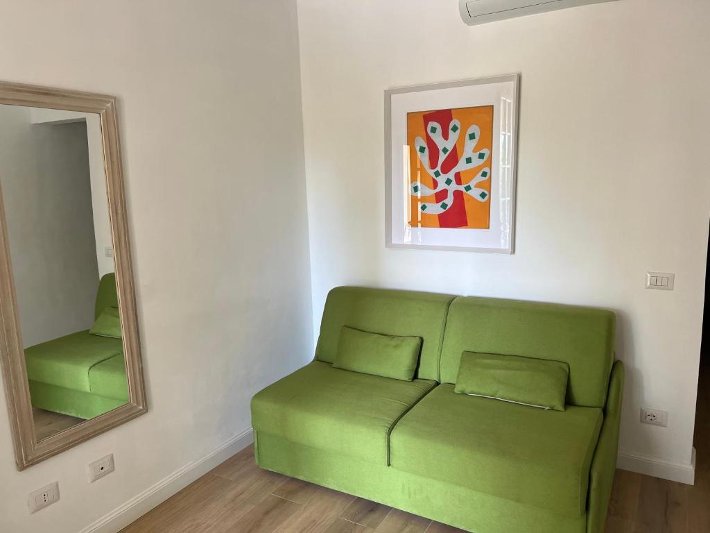 a green couch in a room with a mirror at Maison d'Orange - La Pinede in Saint-Tropez
