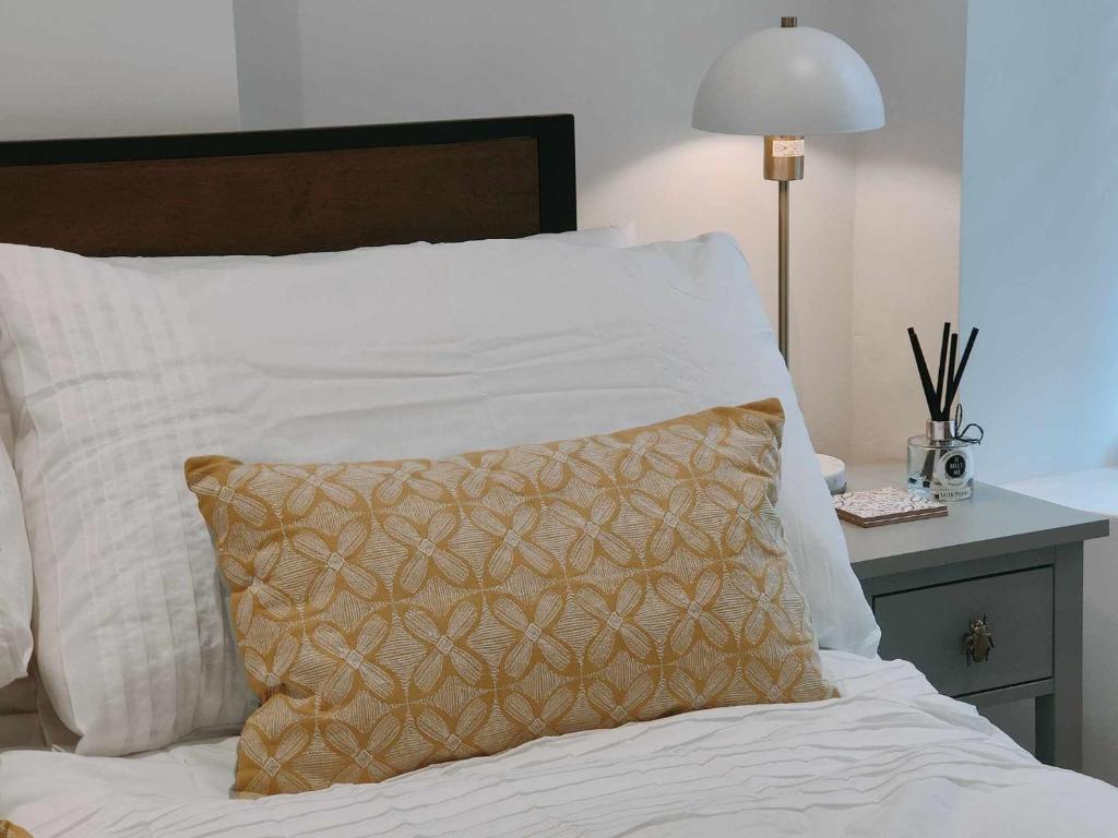 Una cama con sábanas blancas y una almohada. en Queen's Apartment in Cardigan, Cardigan Bay en Cardigan