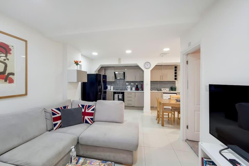 a living room with a couch and a kitchen at Indipendent flat with patio in Greenford