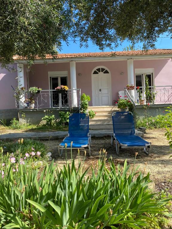 dwa niebieskie krzesła przed różowym domem w obiekcie Marie-Angela HOUSE ARILLAS w Korfu