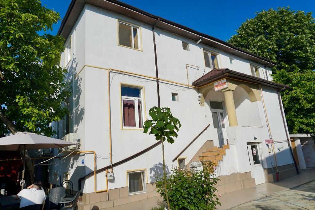 a white building with a staircase next to a table at Vila Alfredo in Craiova