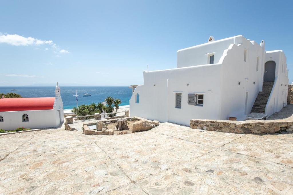 a white building on the beach with the ocean in the background at Blue Moon Mykonos Homes in Mýkonos City
