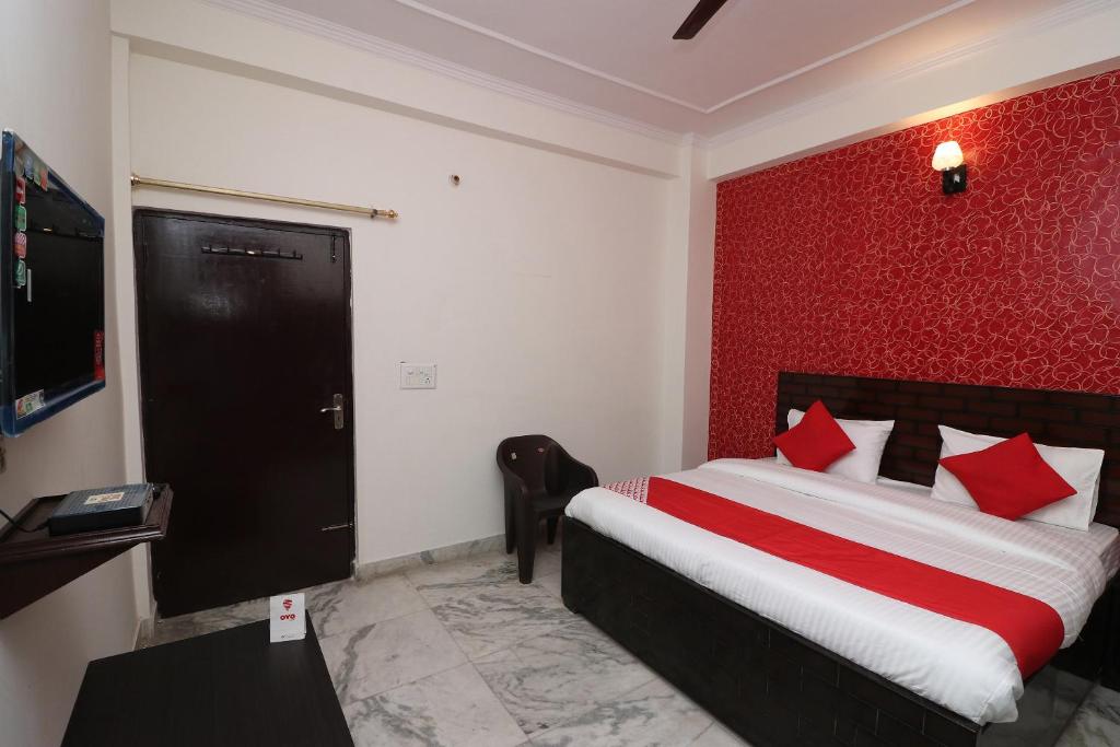 um quarto com uma cama e uma parede vermelha em Collection O Delta Square em Gurgaon