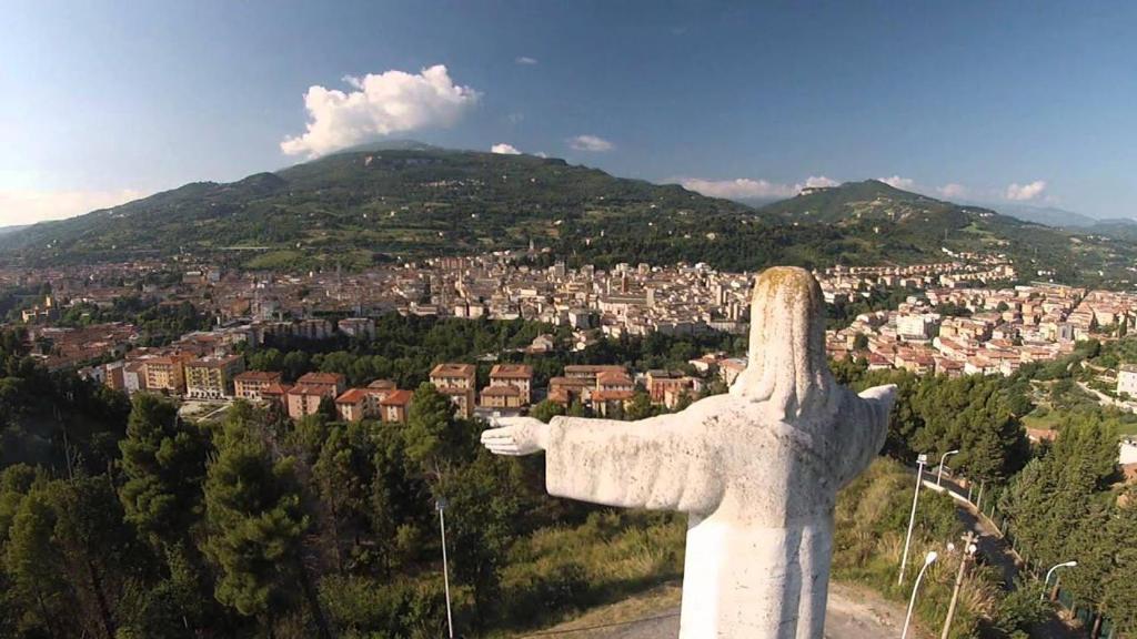 a statue of a christ the redeemer overlooking a city at Rifugio collina del Sacro Cuore in Ascoli Piceno