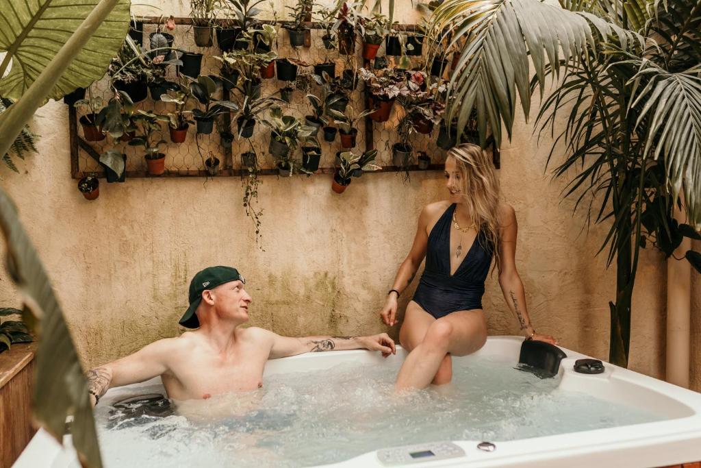 Ein Mann und eine Frau sitzen in einer Badewanne in der Unterkunft myinsolite - Cocon Tropical, jacuzzi, énigme in Vauvert