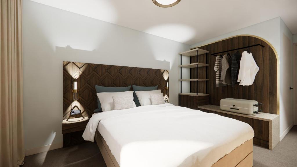 a bedroom with a large white bed with a wooden headboard at Strandhotel de Logerij in Renesse